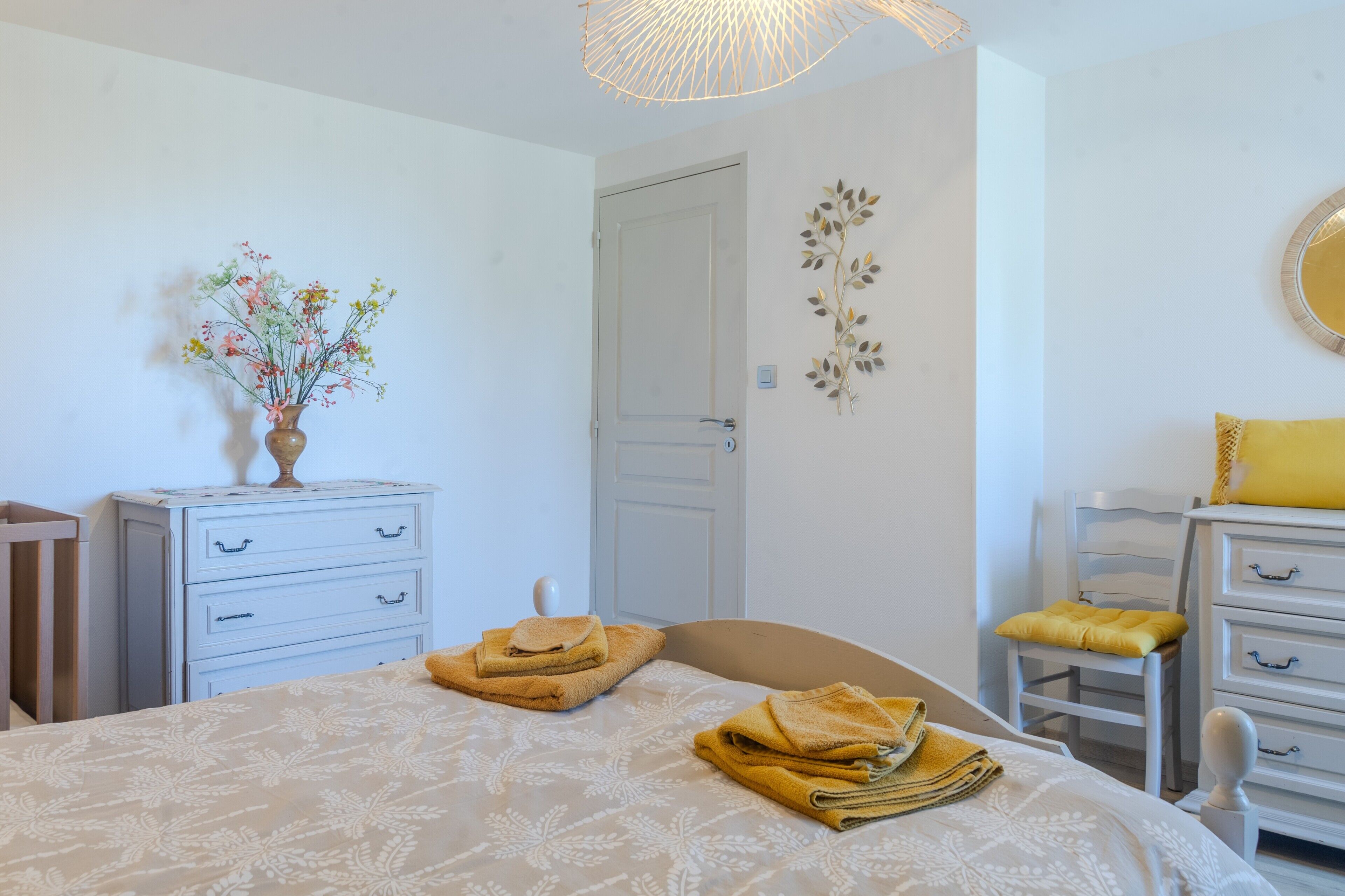 A bedroom with a bed, a dresser, a chair, a door, and a wall decoration.