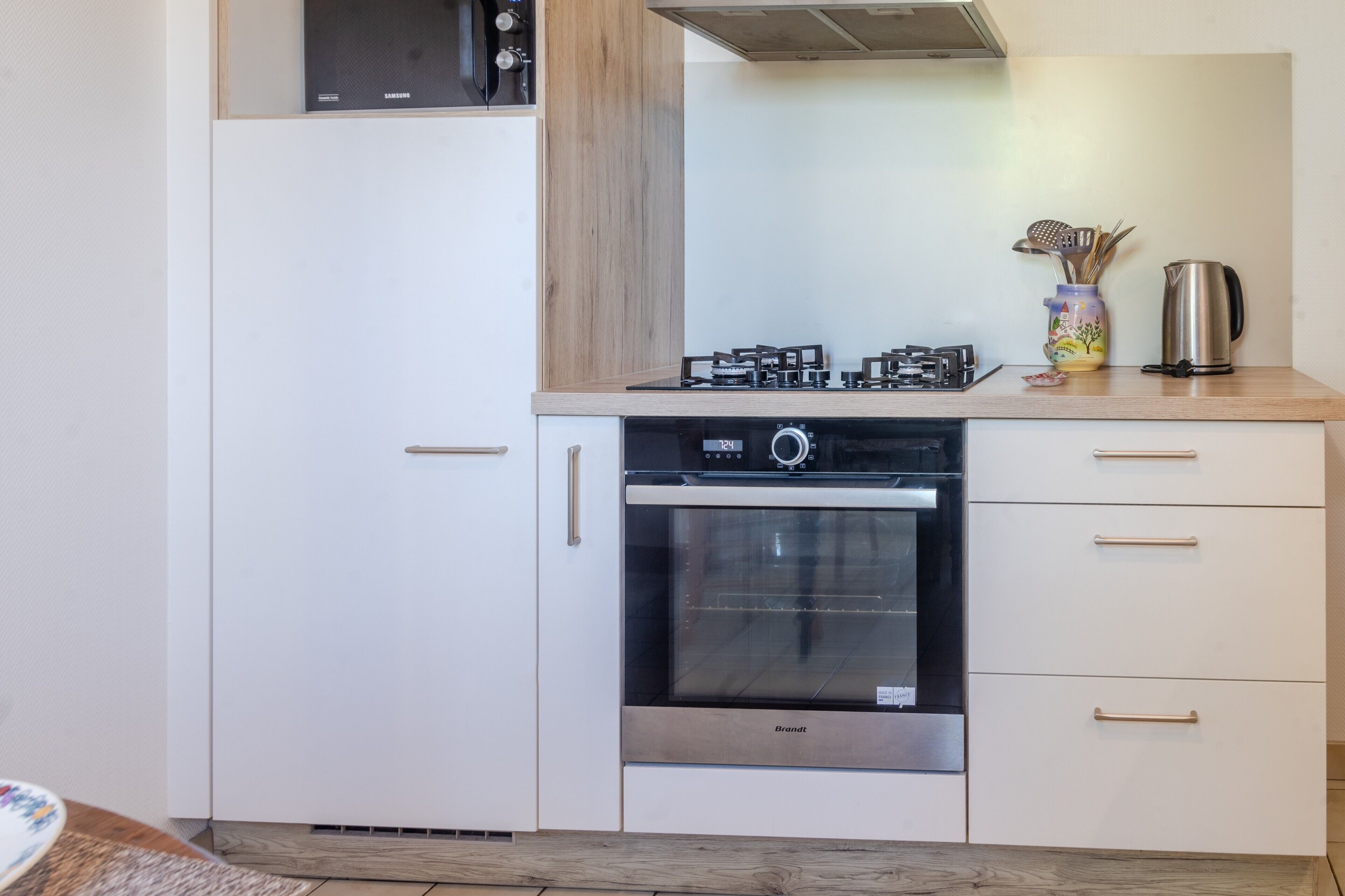 Una cucina compatta con forno a incasso, microonde e piano cottura a gas.
