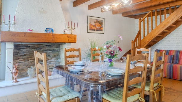 A dining area with a wooden table, chairs, and a fireplace. - Le logis chez bompain (Brizambourg)