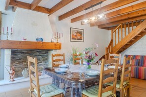 A dining area with a wooden table, chairs, and a fireplace. - Le logis chez bompain (Brizambourg)