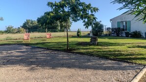A gravel driveway leading to a house with a small tree, a fence, and two chairs in the background. - Le logis chez bompain (Brizambourg)