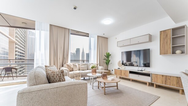 A modern living room with a large TV, a sofa, a coffee table, and a view of a city skyline.