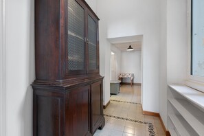 A narrow hallway with a wooden cabinet and a table with a floral tablecloth.