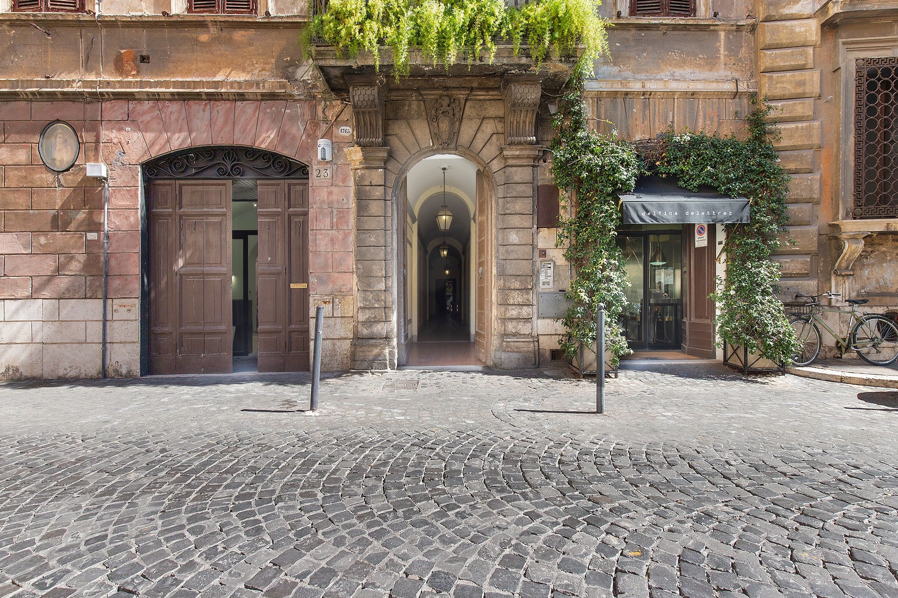 A cobblestone street leading to a building with a large wooden door and an arched entrance.