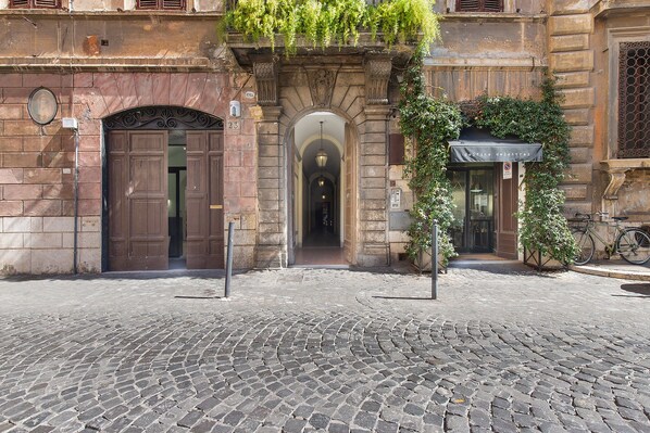 A cobblestone street leading to a building with a large wooden door and an arched entrance. - Memories of yesteryear (Roma)