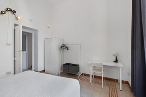 Une chambre d’hôtel équipée d’un lit, d’un bureau, d’une armoire et d’un porte-chaussures suspendu.