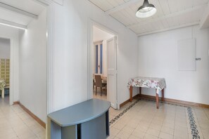 Un couloir avec une table et des chaises, une porte et un sol à motifs.