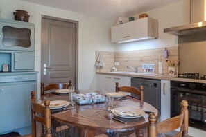 Ein Essbereich mit einem runden Tisch, Stühlen und einer Küche im Hintergrund.