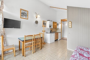 Un espace de vie compact comprenant un coin repas, une kitchenette et un lit.