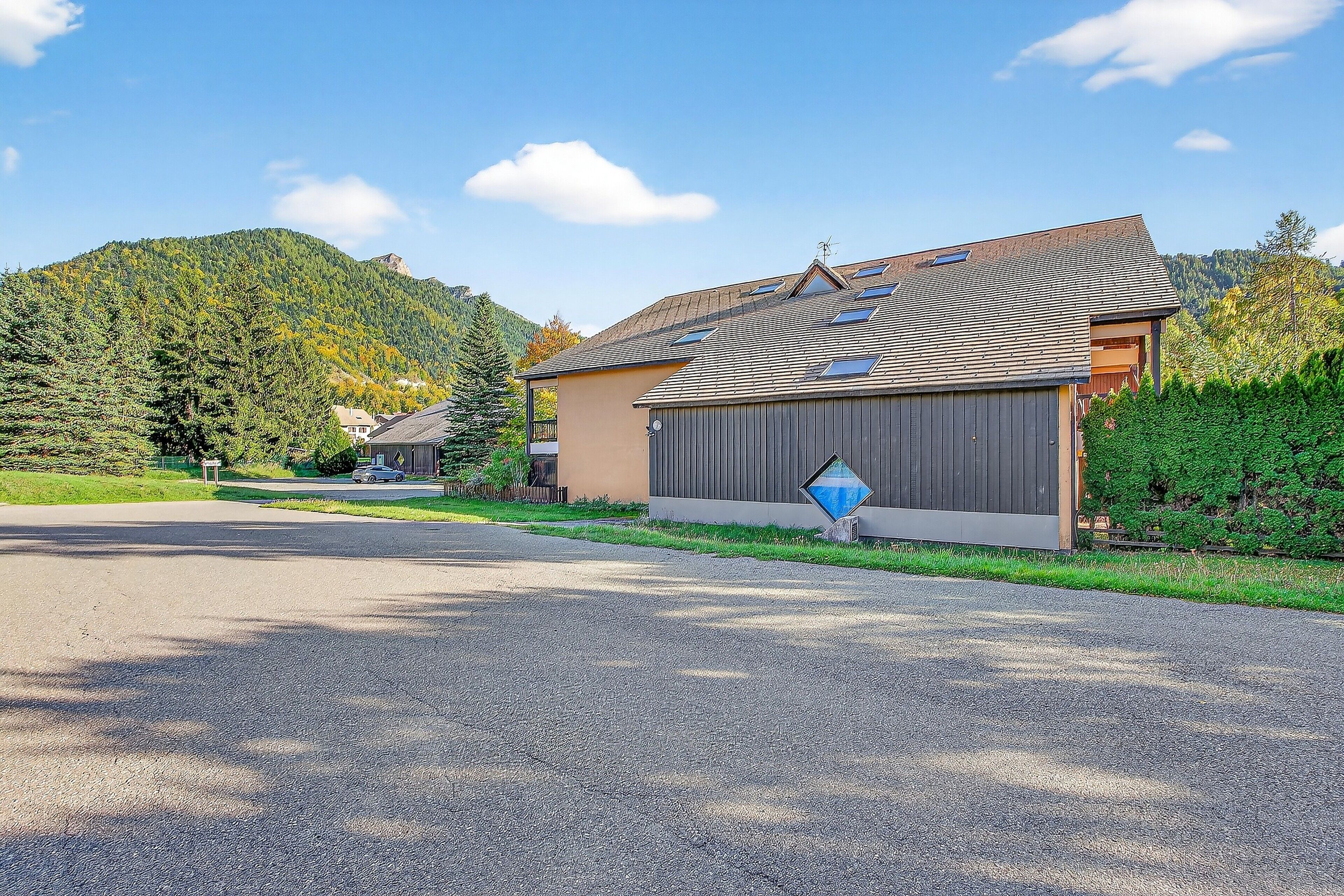 Un immeuble résidentiel doté d’un garage, d’une allée et offrant une vue sur les montagnes.