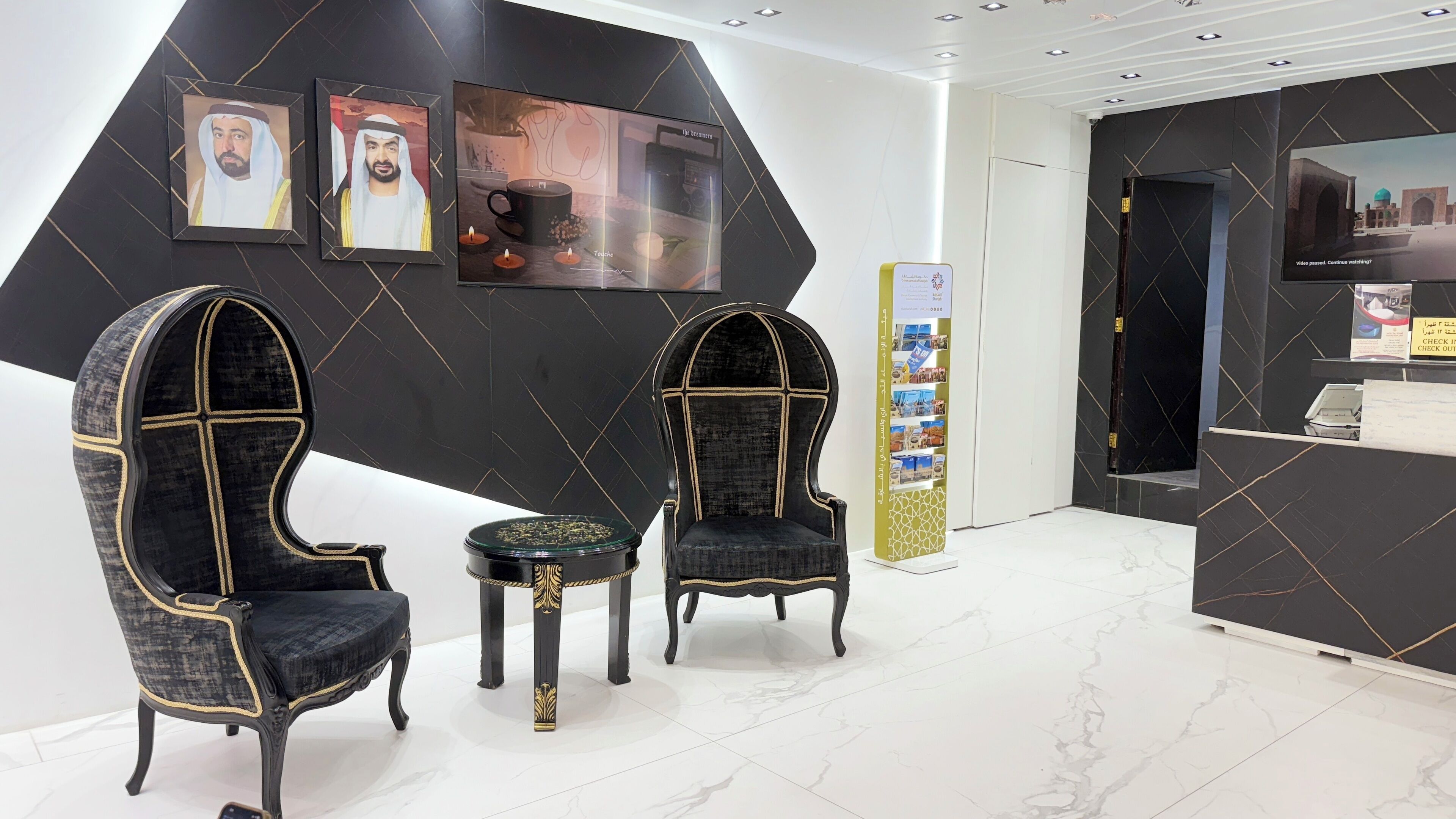 A reception area with two ornate chairs, a small table, and a counter with informational displays.