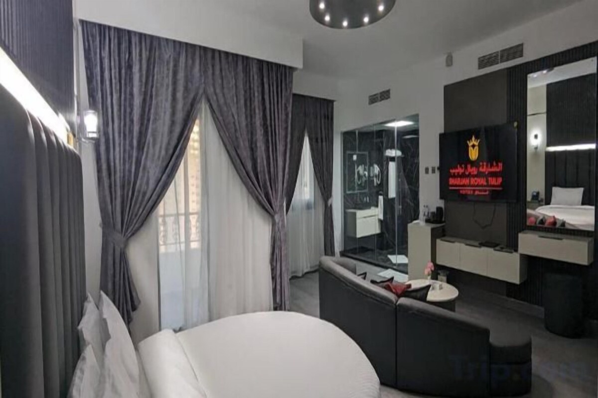 Une chambre d’hôtel moderne équipée d’un lit, d’un canapé, d’une télévision et d’un miroir dans la salle de bain.