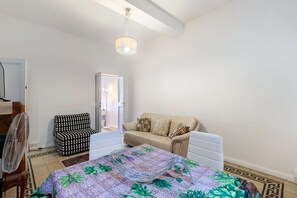 Un dormitorio con cama, una silla, un sofá y una lámpara colgante.