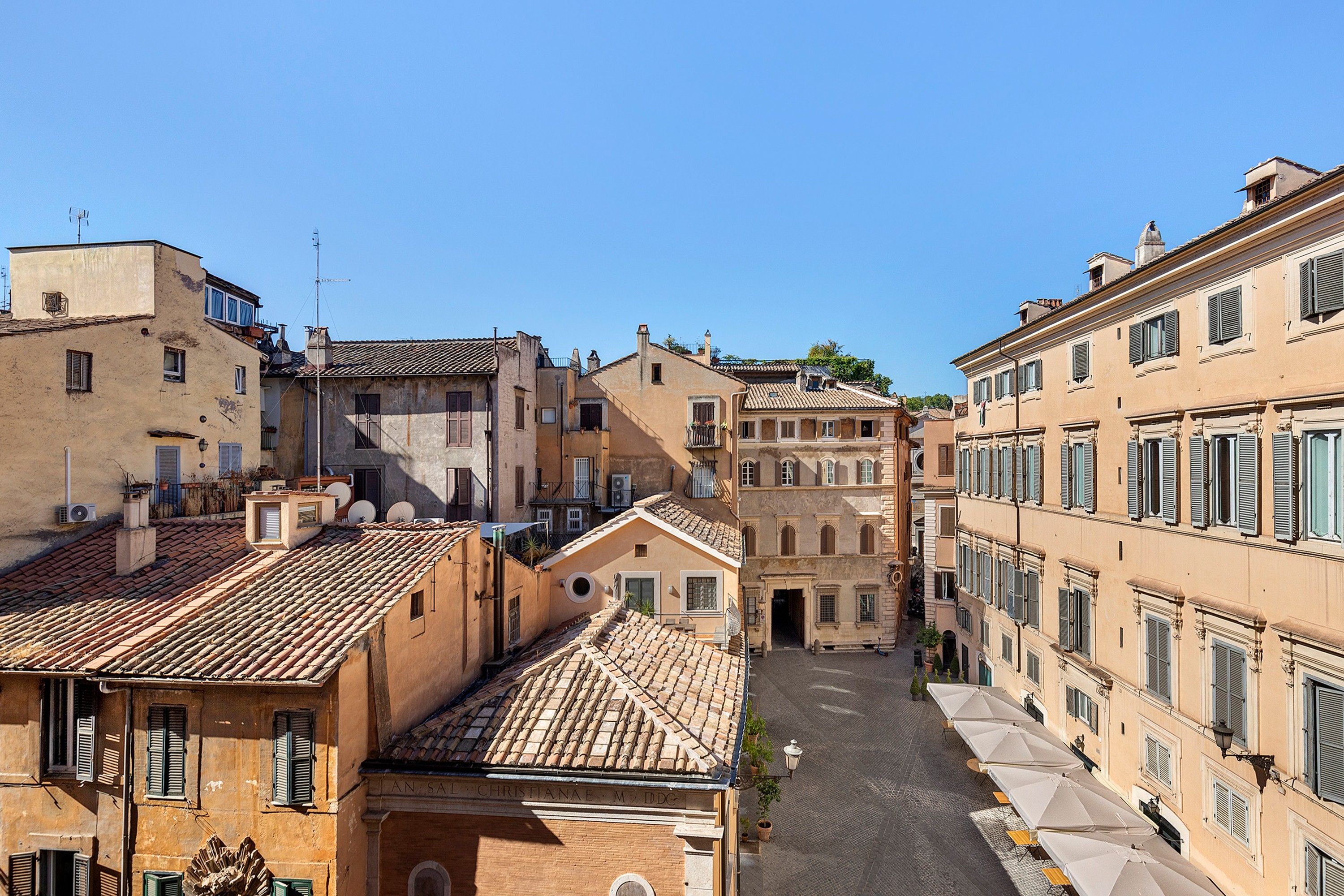 A narrow street flanked by historic buildings with traditional architecture, a cobblestone street, and a clear blue sky.