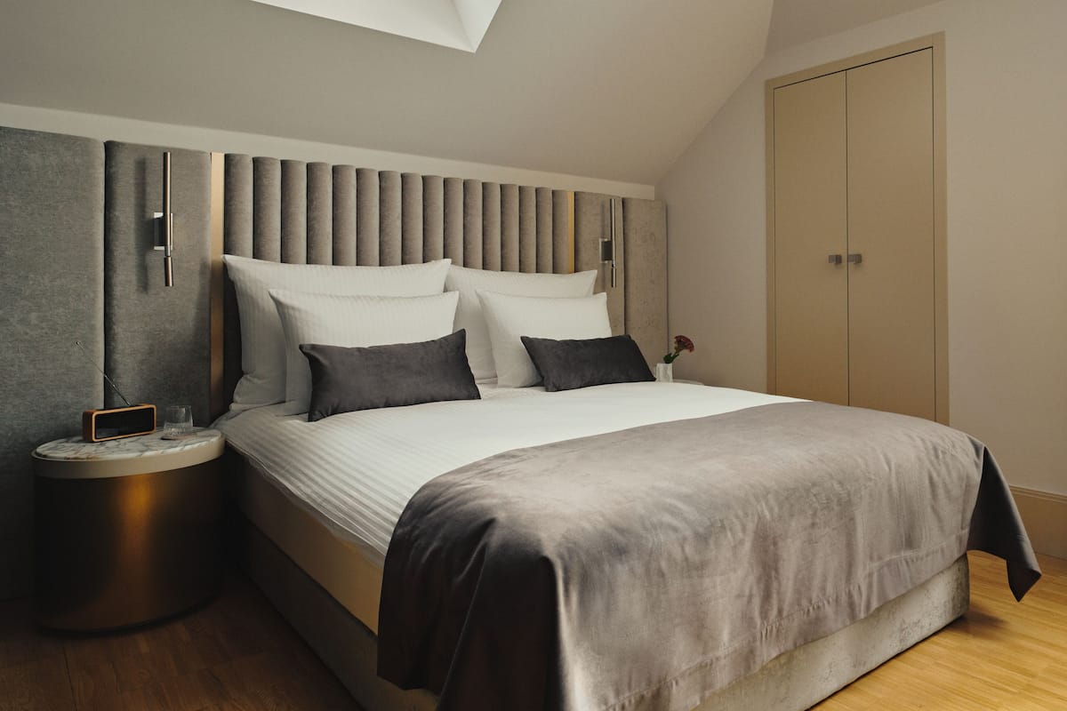 A modern bedroom with a large bed, a bedside table with a lamp, and a wardrobe.
