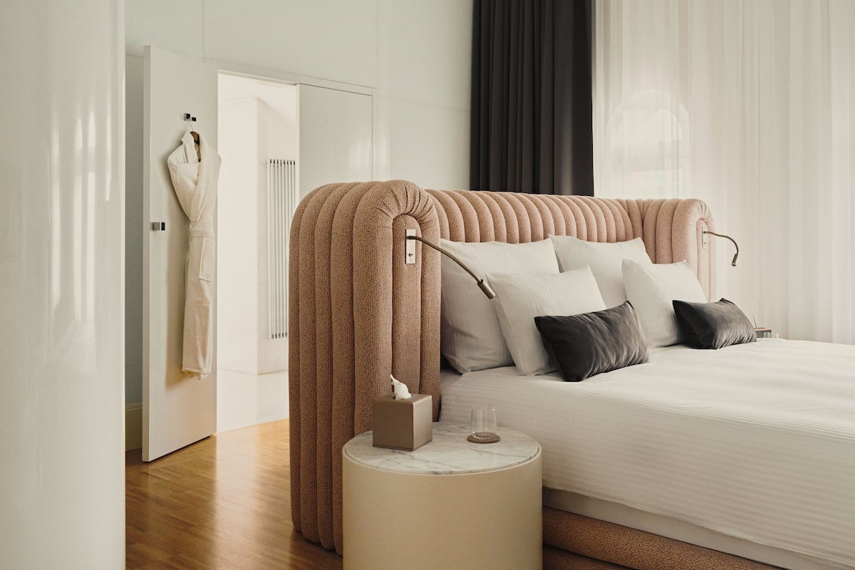 A modern bedroom with a tufted headboard, a bedside table with a lamp, and a neatly made bed.