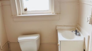Une petite salle de bain avec des toilettes, un lavabo et une fenêtre.