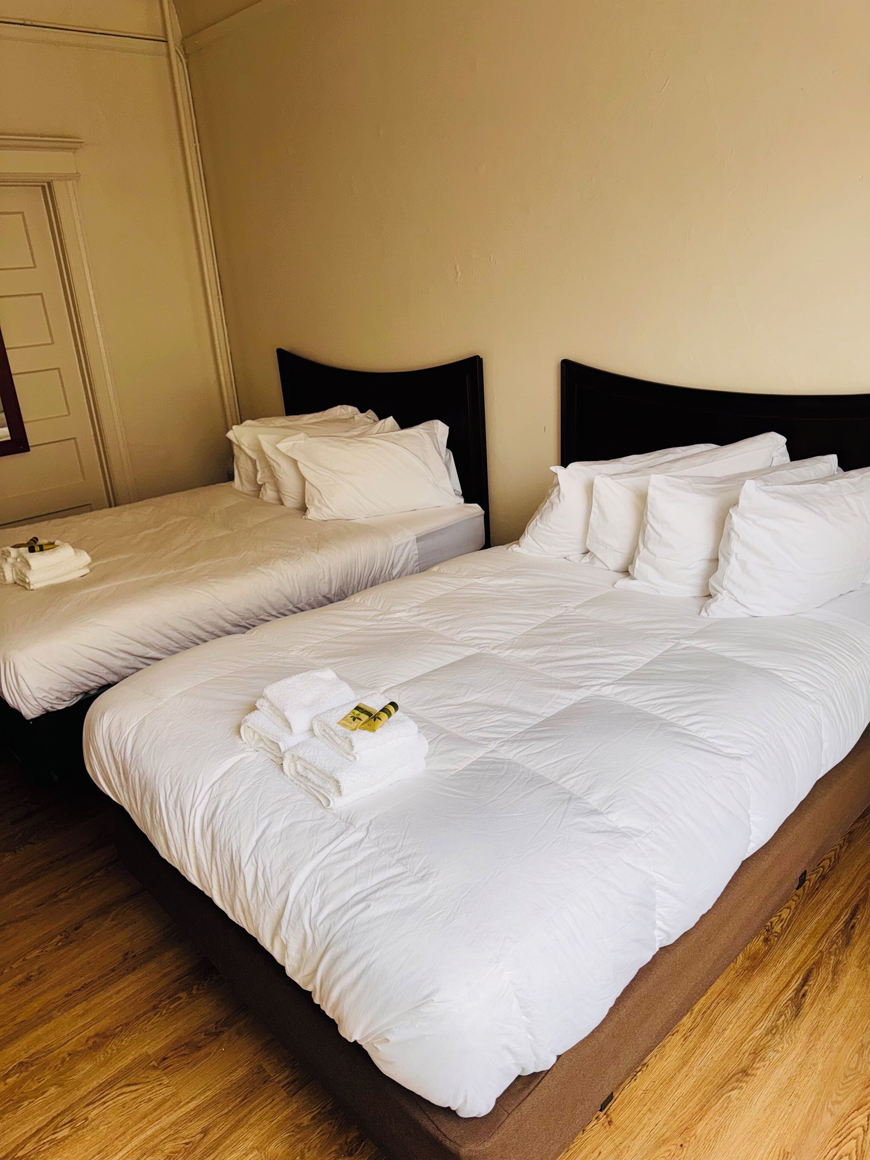Two single beds with white linens and dark headboards in a hotel room.