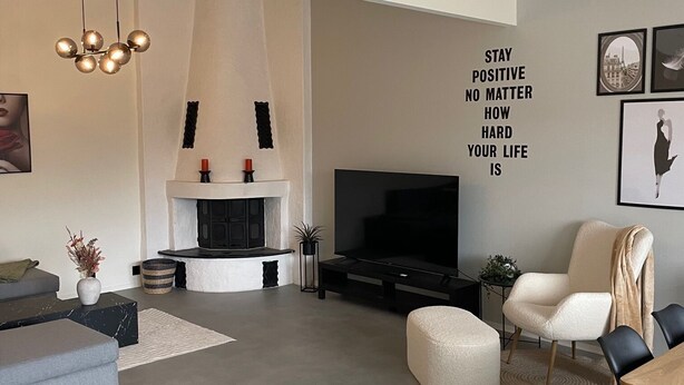 Ein modernes Wohnzimmer mit Kamin, einem großen Flachbildfernseher und einem motivierenden Zitat an der Wand.