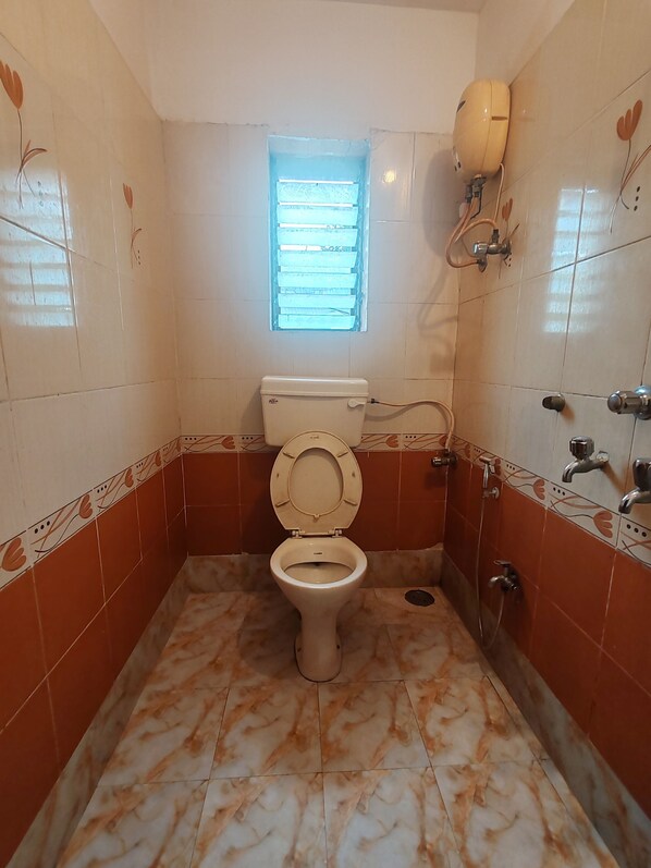 Une salle de bain avec des toilettes, une fenêtre et une douche.