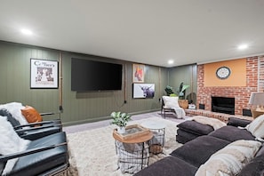 A living room with a flat-screen TV, a fireplace, and a comfortable seating area. - The Glenwood - A Cozy Ranch in Mission, KS (Mission)