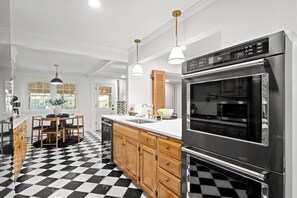 A kitchen with a checkered floor, wooden cabinets, stainless steel appliances, and pendant lighting.