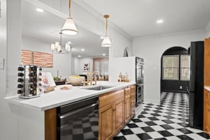 Expansive kitchen island with prep sink, dishwasher, and ample counter space. Ideal for group meals, entertaining, and easy flow between cooking and gathering areas.
