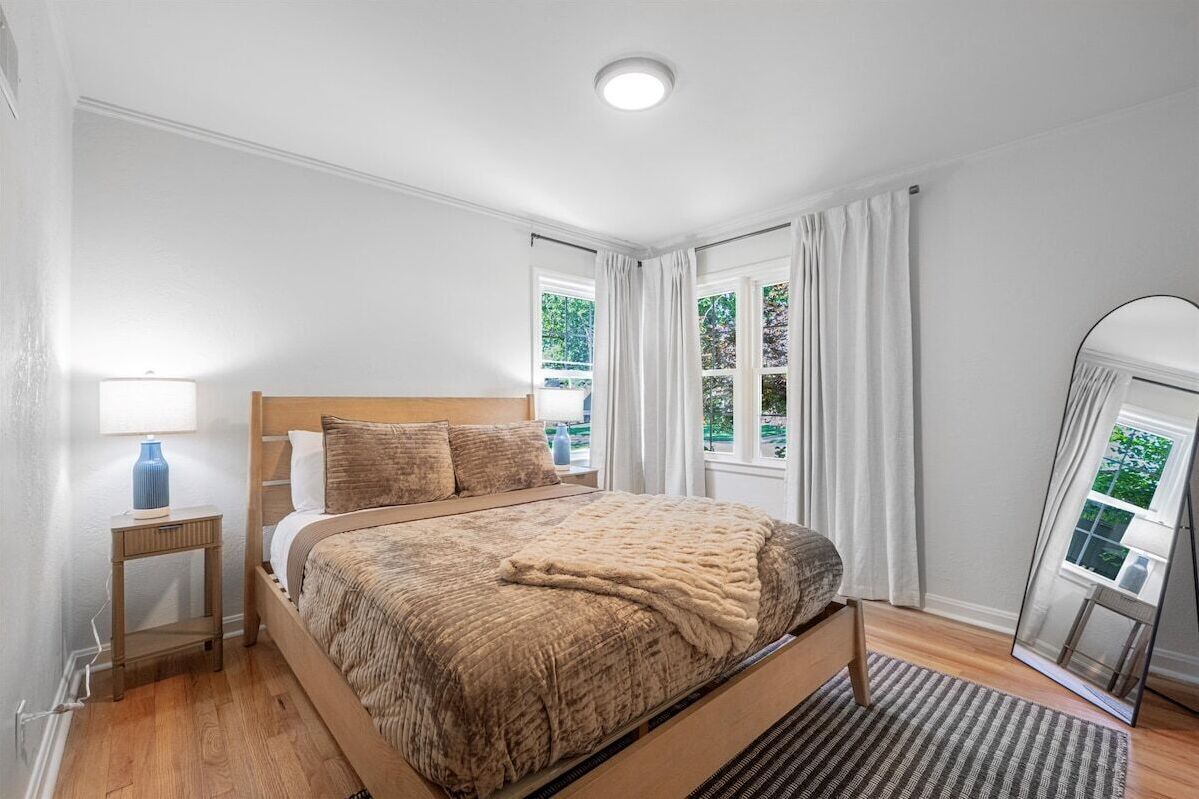 Main-level queen bedroom with hardwood floors, natural light, and cozy bedding. A comfortable and private retreat designed for restful nights during your Kansas City stay.