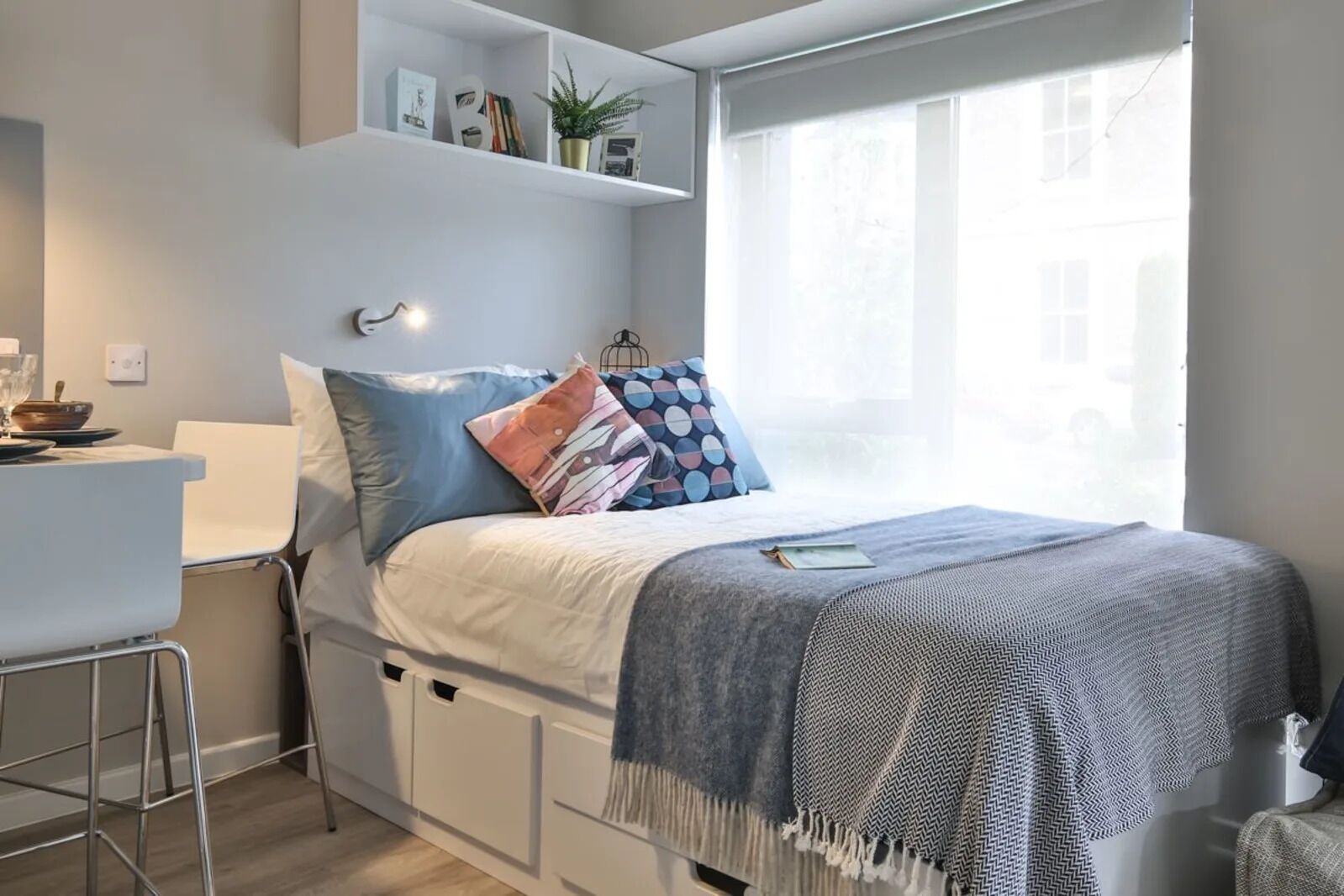 Un dormitorio moderno con una cama, un escritorio y una ventana.