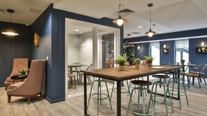 A modern interior with a wooden table and green stools, a striped chair, and potted plants. - Student Only 73 Princess Road East (Leicester)