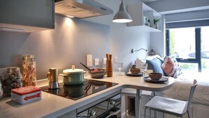 A modern kitchen with a central island, a built-in oven, and a dining area with a chair and table. - Student Only 73 Princess Road East (Leicester)
