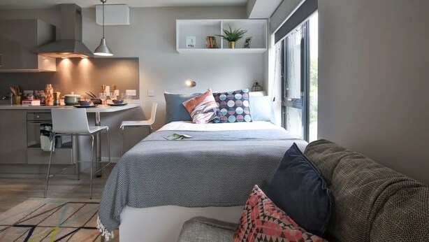 A modern, compact living space with a kitchenette, a dining area, and a bed with a view. - Student Only 73 Princess Road East (Leicester)