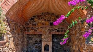 A stone-walled room with a brick arch, a small arched niche, and a stone floor. - Villa Poggio al Coniglio at Suvereto with Pool (Suvereto)