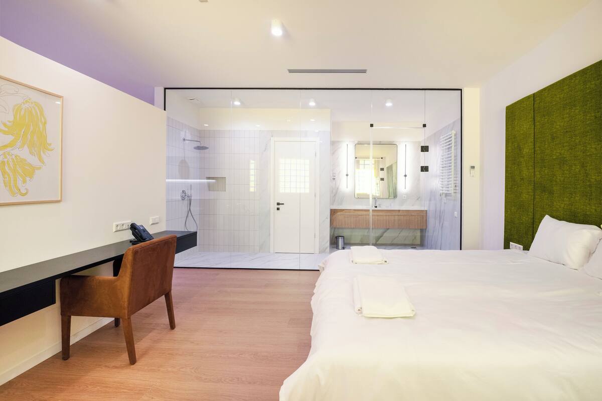 Een moderne hotelkamer met een bed, een bureau en een douche.
