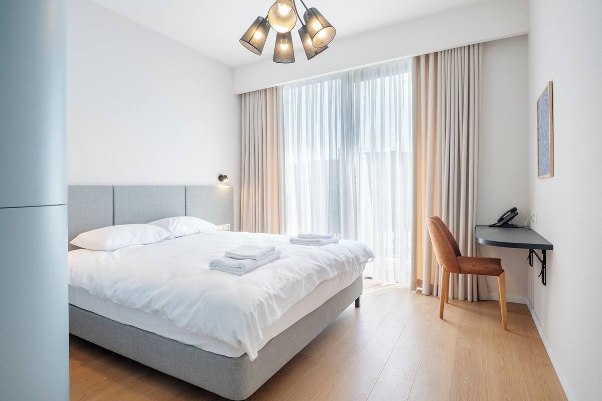 Een moderne hotelkamer met een groot bed, een bureau en een stoel.