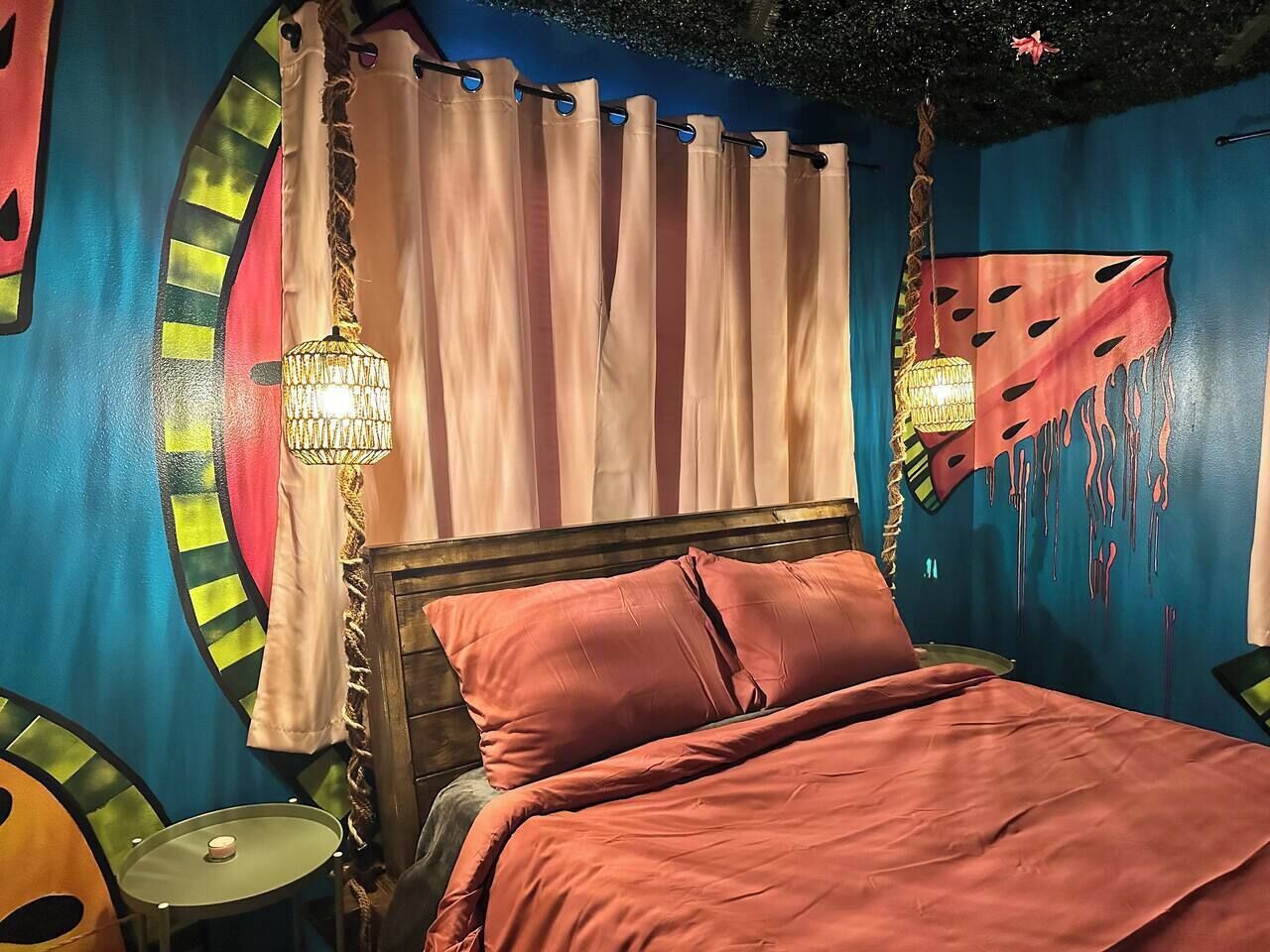 A bedroom with a bed, curtains, and a wall mural.