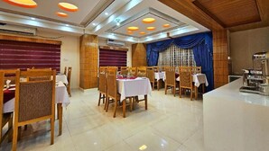 Un restaurante con muebles de madera, manteles blancos y un diseño de techo moderno.