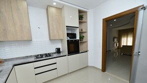 A modern kitchen with white cabinets, a black stove, and a microwave.