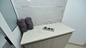 A kitchen with a white countertop, a tiled backsplash, and a cabinet below.