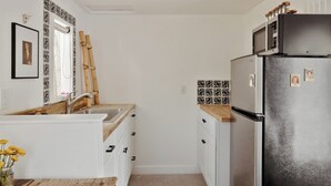 A compact kitchen with white cabinets, a stainless steel refrigerator, and a wooden countertop. - Quaint Phoenix Hideaway: Spanish Charm (Phoenix)