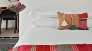 A room with a bed, a hanging macrame piece, a wooden bowl with flowers, and a large horn on the wall. - Quaint Phoenix Hideaway: Spanish Charm (Phoenix)
