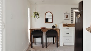 A kitchen with a wooden countertop, two black chairs, a hanging plant, a mirror, and a refrigerator. - Quaint Phoenix Hideaway: Spanish Charm (Phoenix)