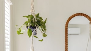 A wooden table with a bowl and a macrame plant hanging above it. - Quaint Phoenix Hideaway: Spanish Charm (Phoenix)
