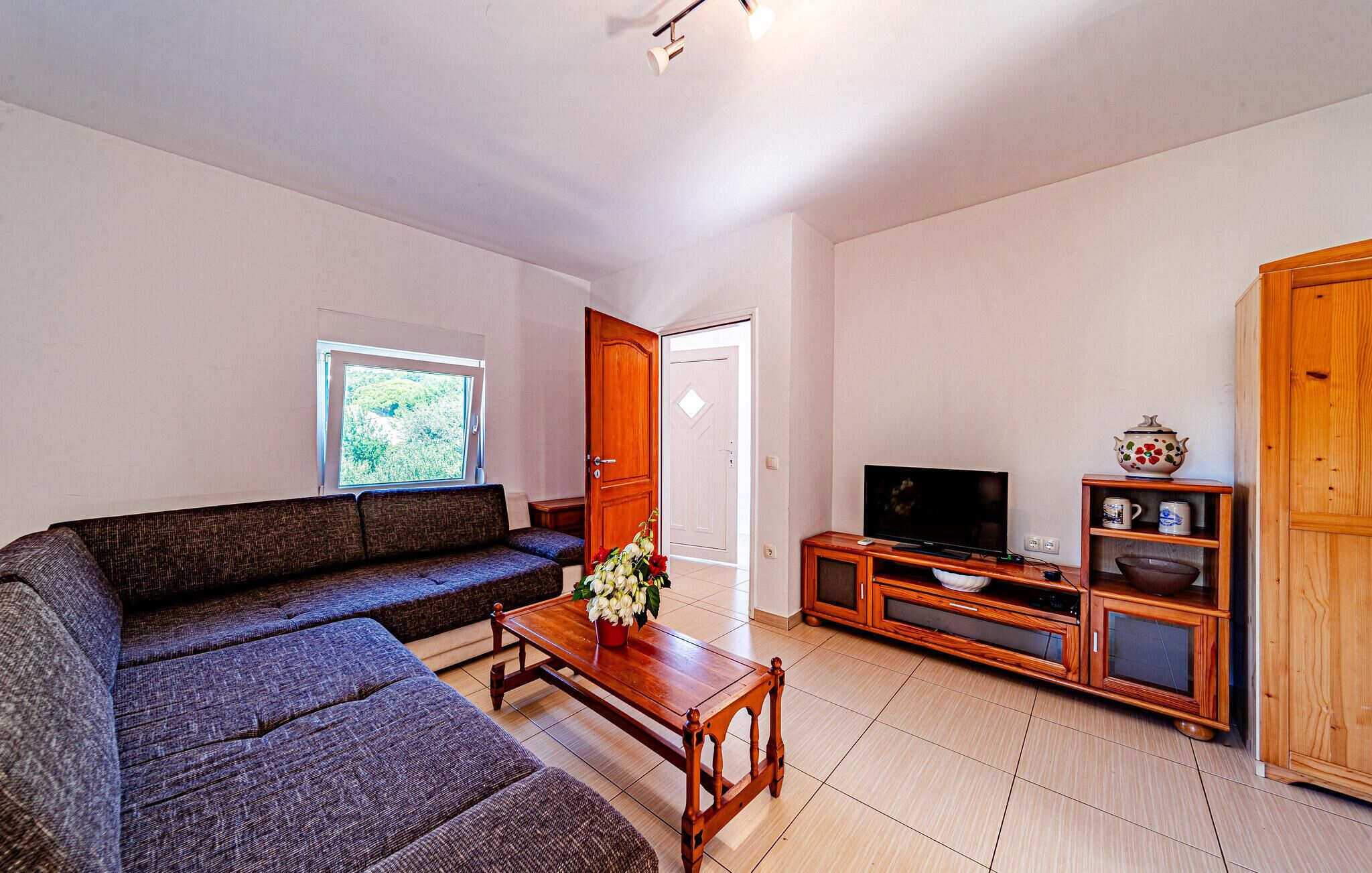 A living room with a sectional sofa, a wooden coffee table, a TV stand, and a cabinet.