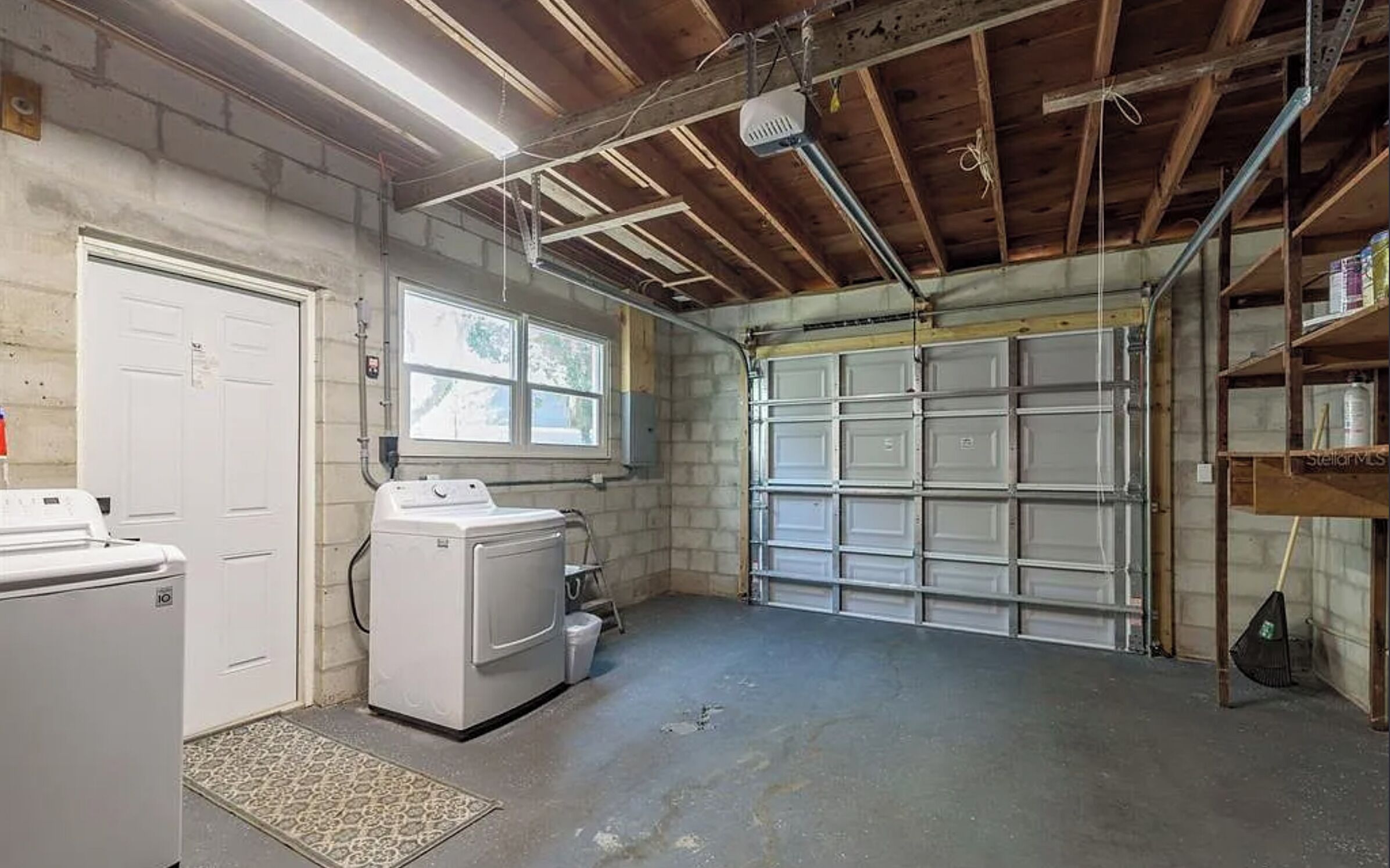 A garage with a washing machine, a dryer, and a window.