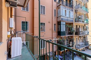 Un balcon avec un radiateur blanc, une rambarde en métal et une rangée de vélos garés en contrebas.