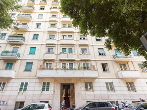 Un edificio de varios pisos con balcones, una entrada central y una escalera que conduce a la entrada.