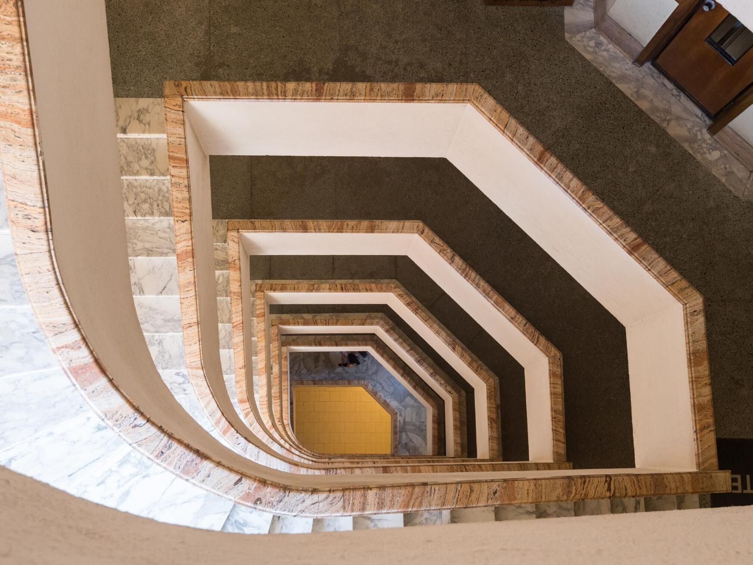 Un escalier en colimaçon avec un sol en marbre et une structure en bois.