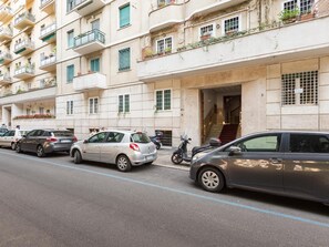 Een meerlaags woongebouw met balkons, een trap en geparkeerde auto's.