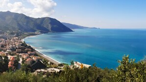 A coastal town with a beach, buildings, and mountains.